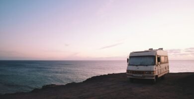 RV parked beside the edge of island during sunset