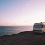 RV parked beside the edge of island during sunset